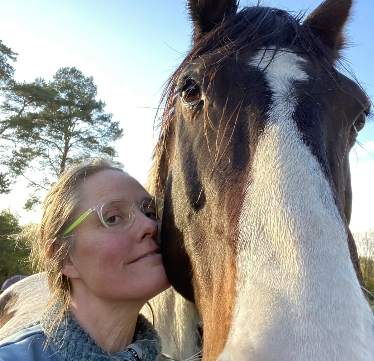 Jessica Bergman tillsammans med en häst utomhus i kvällsljus