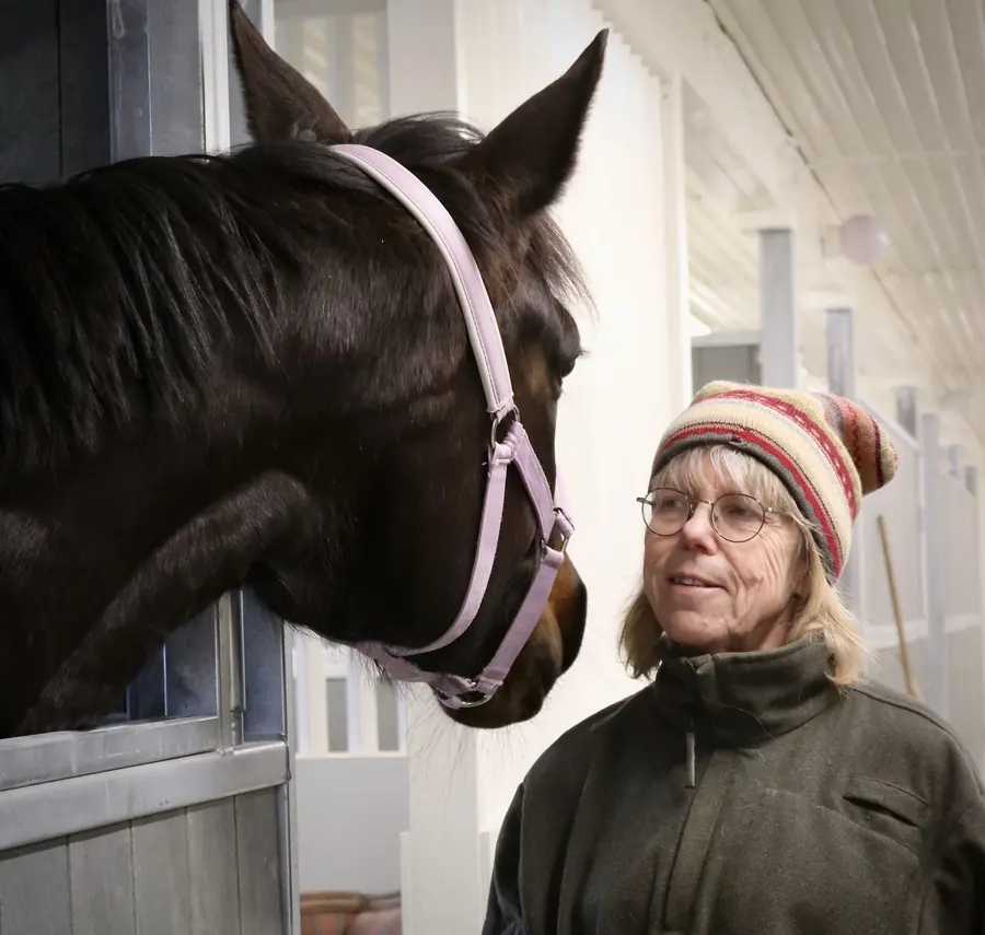 Lena Söderberg tillsammans med en häst i en box på kliniken